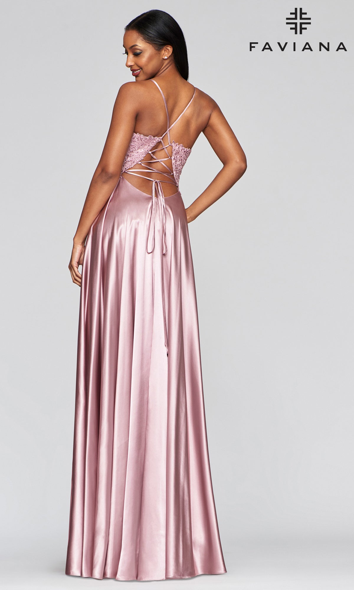 A woman in the Faviana Lace-Bodice Long A-Line Prom Dress, featuring a lace-up open back and subtle embroidered lace details, looks over her shoulder. Faviana logo appears in the top right corner.